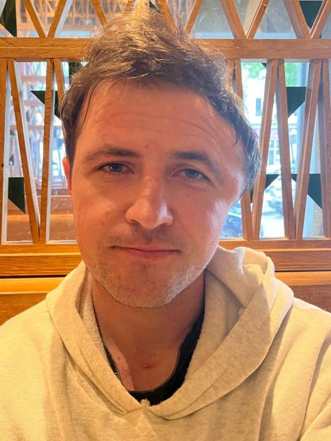 Portrait of a man wearing a light beige hoodie.