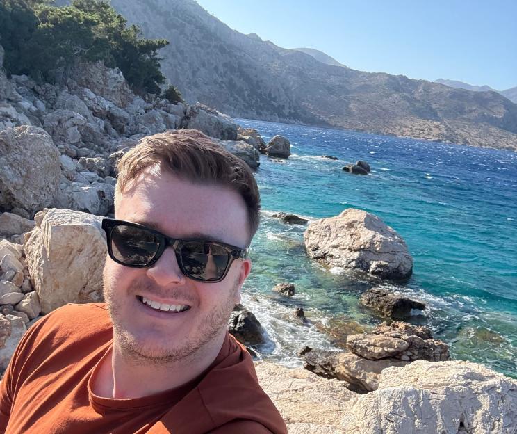 Selfie of a man wearing sunglasses near the ocean.
