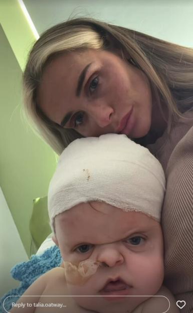 A woman comforting her baby son, who is wearing a bandage on his head.