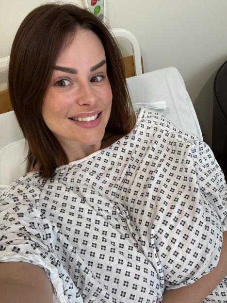 Woman in hospital gown smiling at camera.