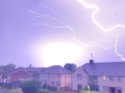 Lightning striking over houses.