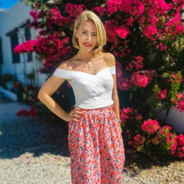 Woman in white off-the-shoulder top and floral skirt.