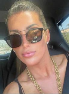Sara Jacqueline King in a car, wearing sunglasses and a gold necklace.