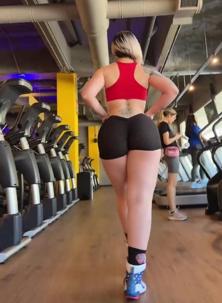 Woman in gym attire walking past exercise machines.