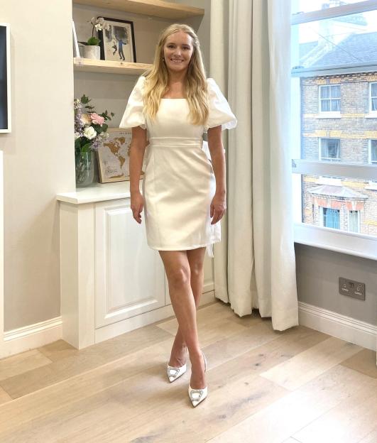 Woman in white dress with bow back detail.
