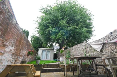 Backyard with large oak tree, garden shed, and patio furniture.