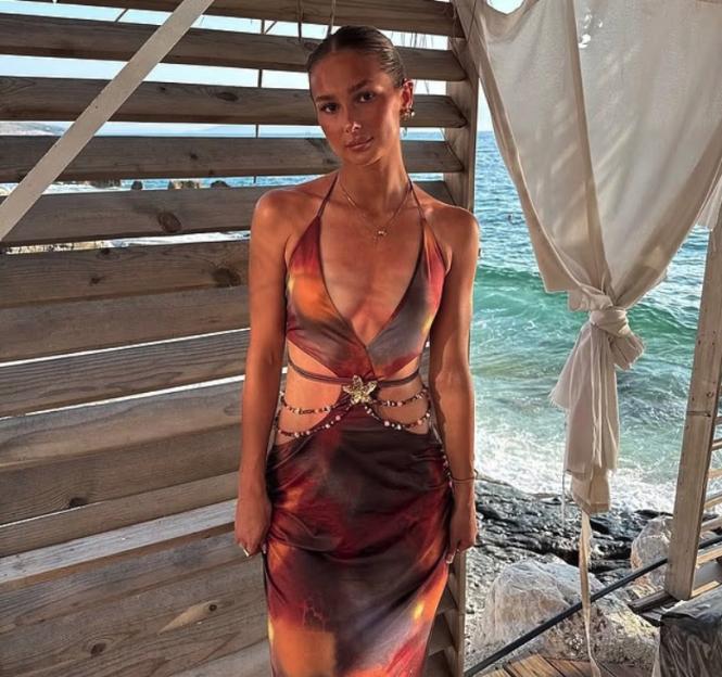 Woman in tie-dye cut-out dress by the ocean.