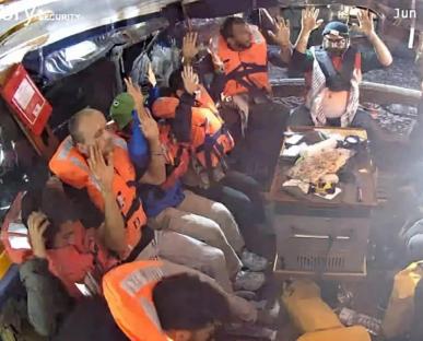 People wearing life vests crowded inside a small boat.