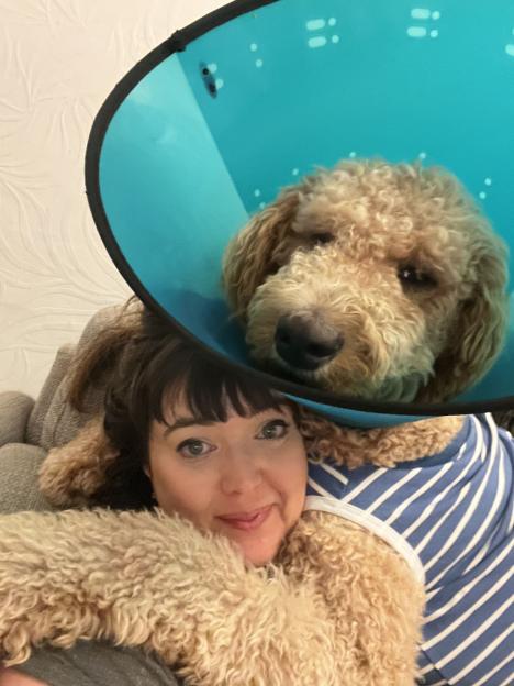 Woman hugging large dog wearing a cone.