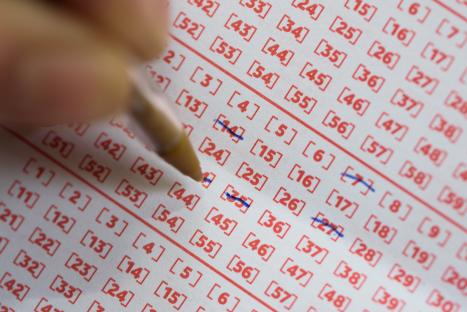 Close-up of a hand filling out a lottery ticket.