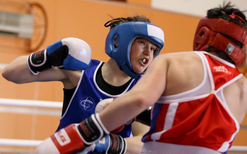 Two female boxers facing each other in a boxing match.