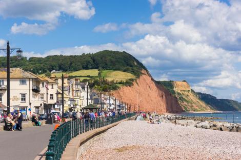 Panoramic view of Sidmouth's seafront, beach, and coastline.