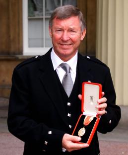 Sir Alex Ferguson holding his knighthood medal.