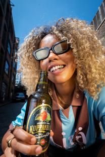 Person with gold teeth holding a bottle of Kopparberg cider.