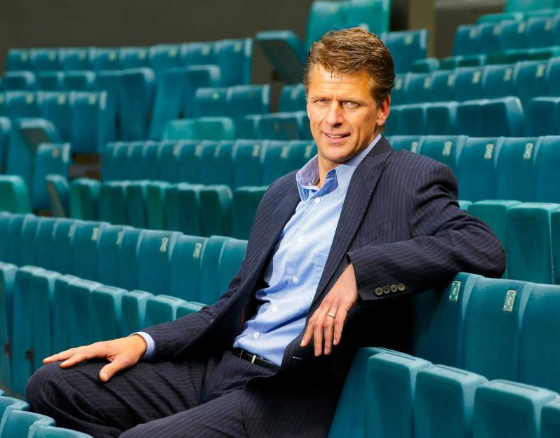 Photo of Andrew Castle, a broadcaster and retired professional tennis player, sitting in stadium seats.