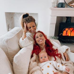 Two women and a baby cuddling on a cream-colored couch.