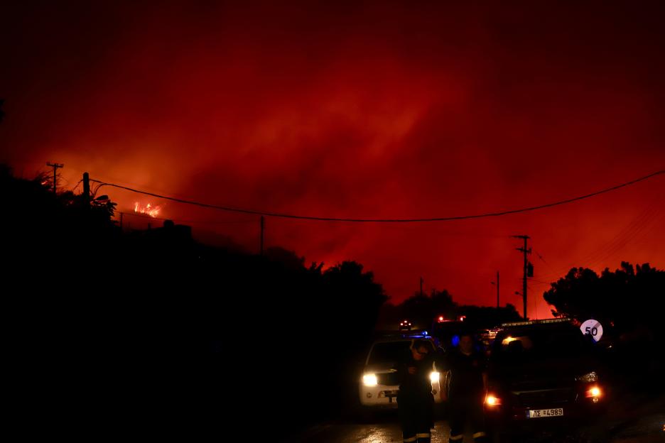 Firefighters and volunteers battling a large wildfire at night.
