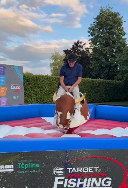 Man riding a mechanical bull at a fishing competition.