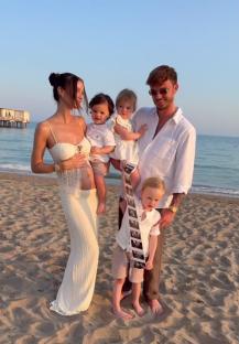 Family on beach announcing pregnancy with ultrasound image.