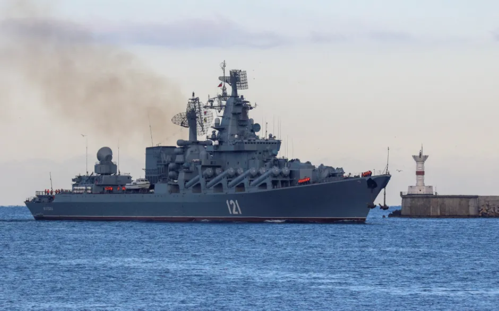Russian Navy cruiser Moskva sailing past a lighthouse.