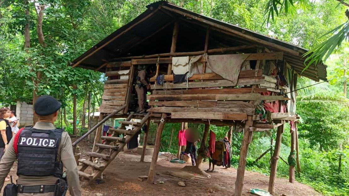 Police officers at a dilapidated wooden house in a wooded area.