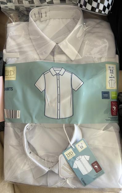 Two white short-sleeve shirts in plastic packaging.
