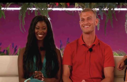 A man and woman smiling on a couch.