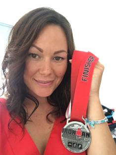 Woman holding Ironman Austria 2017 finisher medal.
