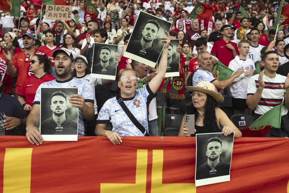 Soccer fans hold photos of Diogo Jota at a Portugal game.
