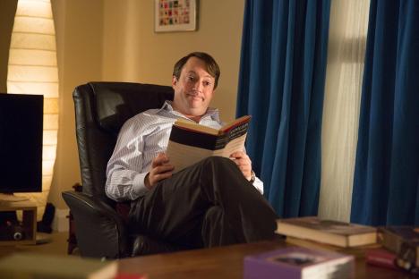 Mark Corrigan from Peep Show reading a book.