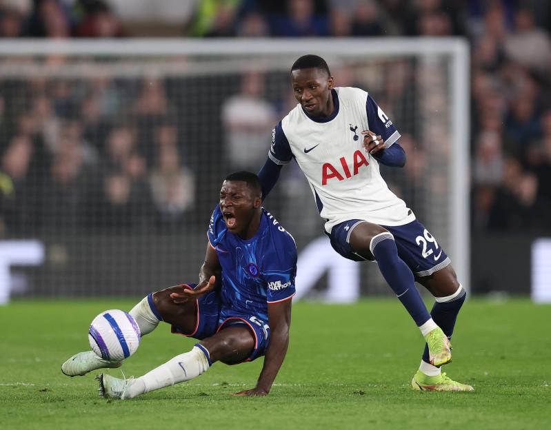 Moises Caicedo of Chelsea challenged by Pape Matar Sarr of Tottenham Hotspur during a soccer match.