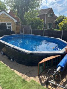 DIY 18ft backyard pool partially surrounded by black plastic.