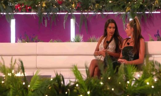 Two women sitting on a couch, talking.