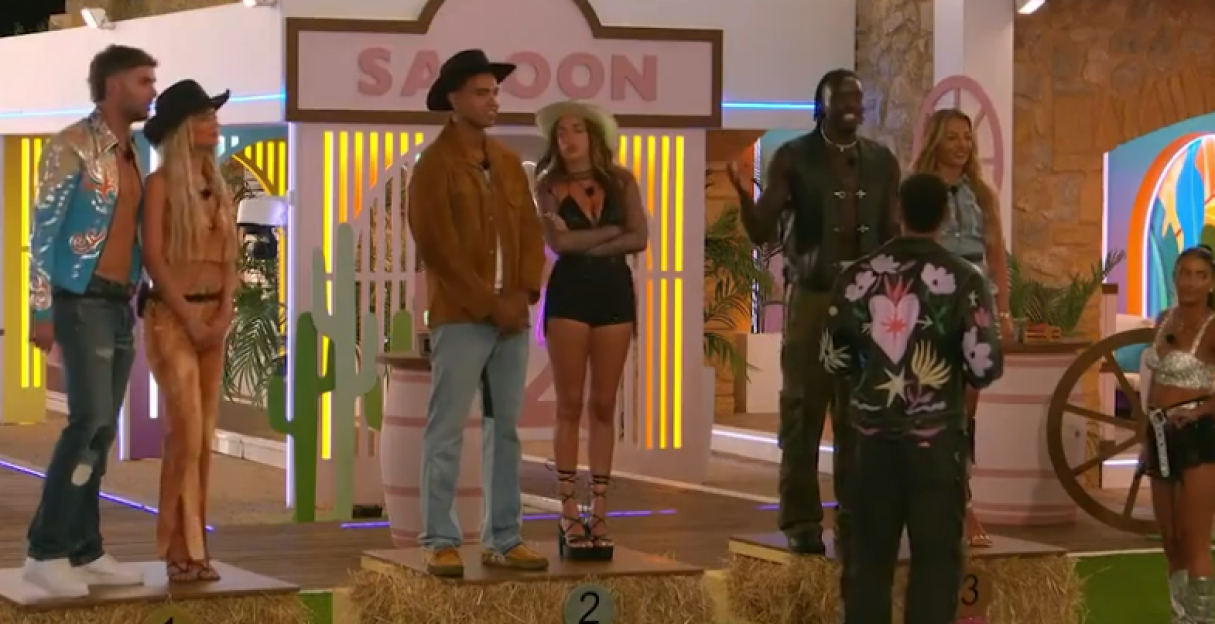 Screenshot of contestants on a reality show game show set.
