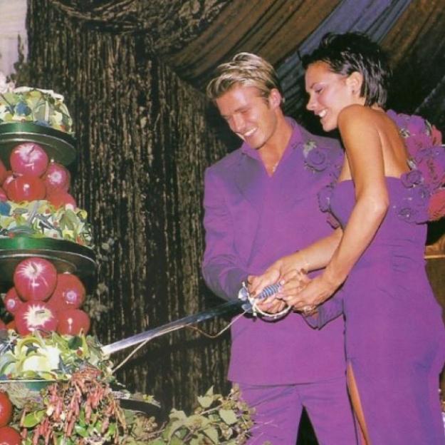 David and Victoria Beckham cutting their wedding cake with a sword.