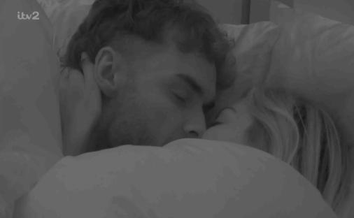 A couple kissing in bed.