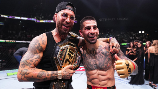 Two MMA fighters celebrating a victory with a championship belt.