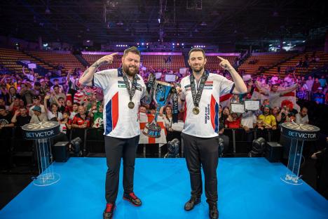 Michael Smith and Luke Humphries, winners of the World Cup of Darts, holding the trophy.