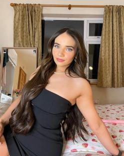Woman with long brown hair wearing a black dress.