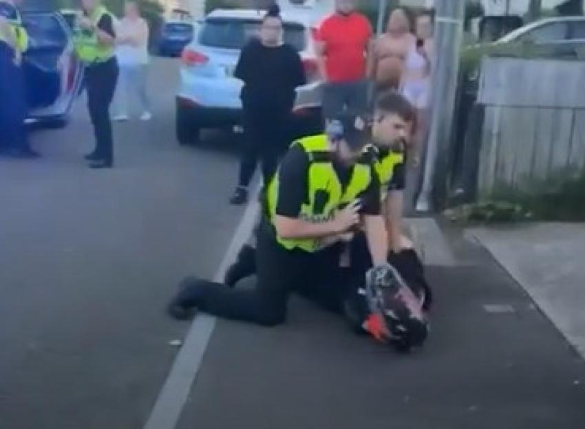 Police officer subduing a biker on the ground.