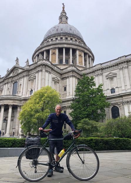 Man standing with his bicycle in front of St. Paul's Cathedral.