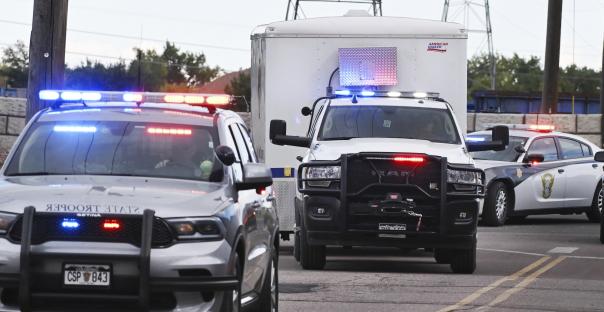 Police escorting refrigerated trucks carrying human remains.