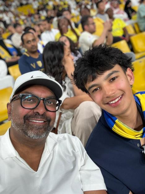 Man and teen smiling at a sporting event.