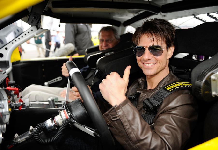 Tom Cruise and his father-in-law giving thumbs up while sitting in a race car.