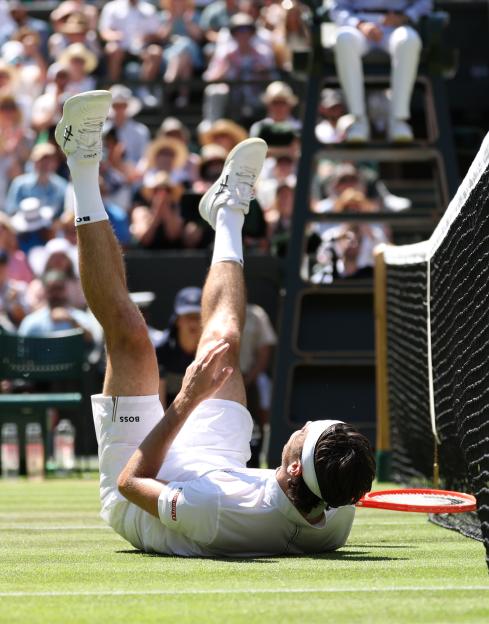 Taylor Fritz of the United States falls during a Wimbledon tennis match.
