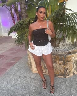 Woman in black corset top and white ruffled shorts.