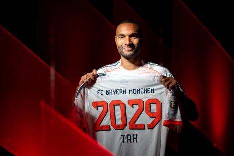 Jonathan Tah holding up his FC Bayern München jersey.