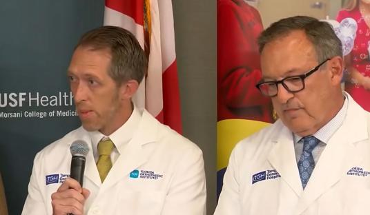 Two doctors in white coats give a press conference.
