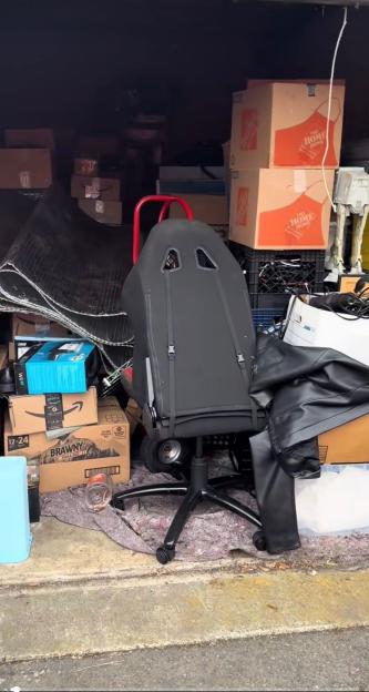Storage unit filled with boxes, a racing seat, and other items.