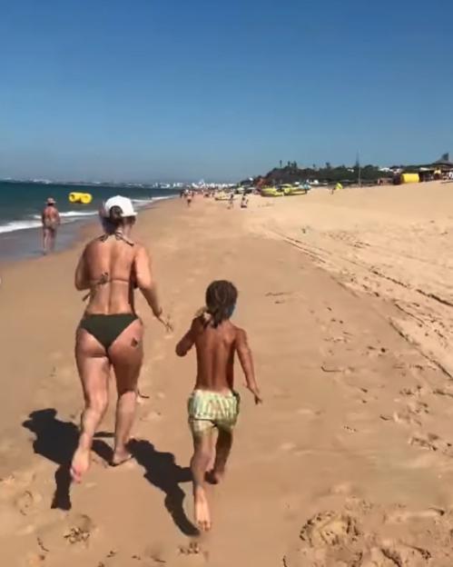 Woman and child running on a beach.